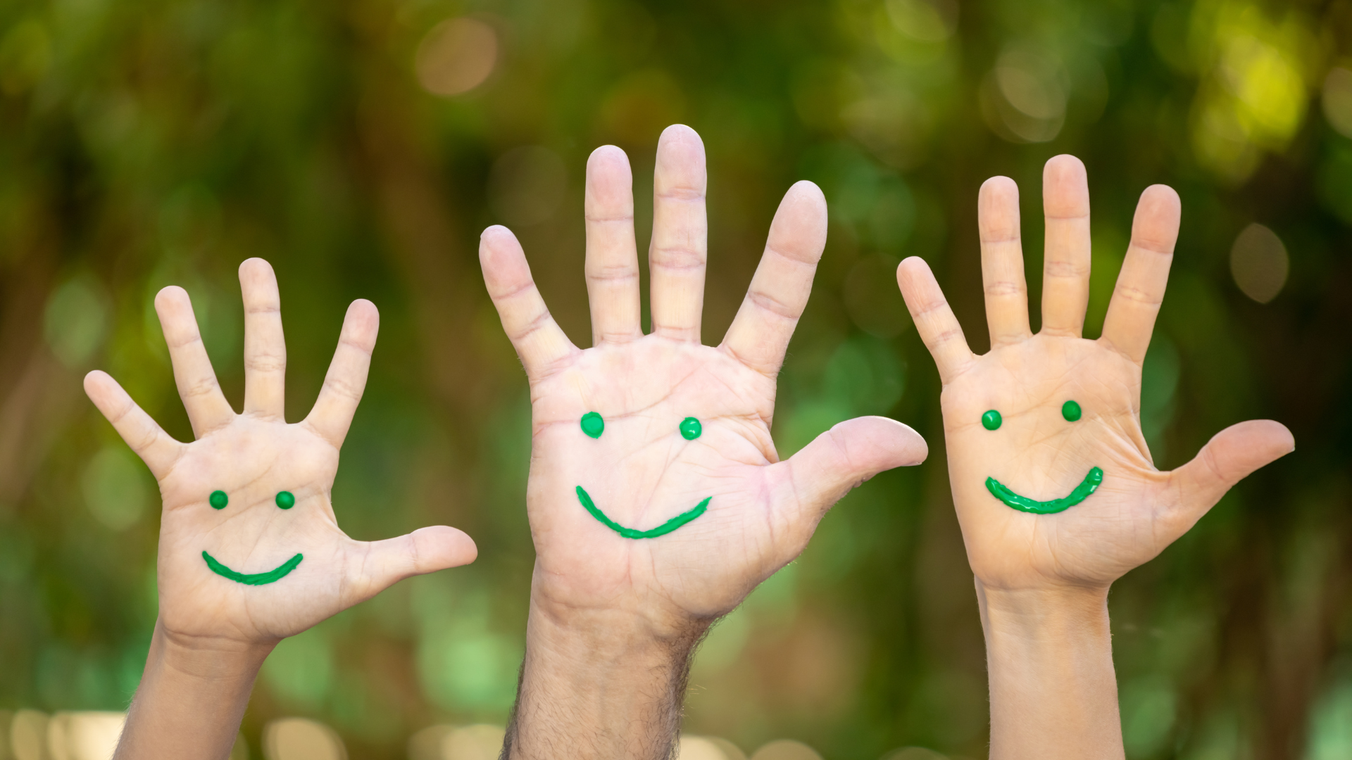 3 hands raised with a green smiley drawn on it